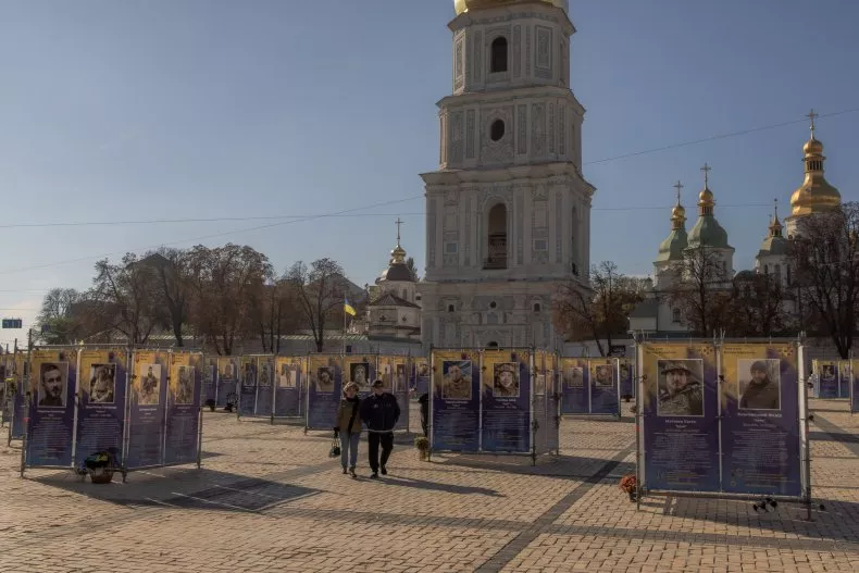 People walk past posters depicting Ukrainian servicemen killed during Russia's invasion at an open-air exhibition in Kyiv on October 20, 2024. South Korean media claims Seoul could send military and intelligence personnel to Ukraine after the North dispatched troops to support Russia in the war.